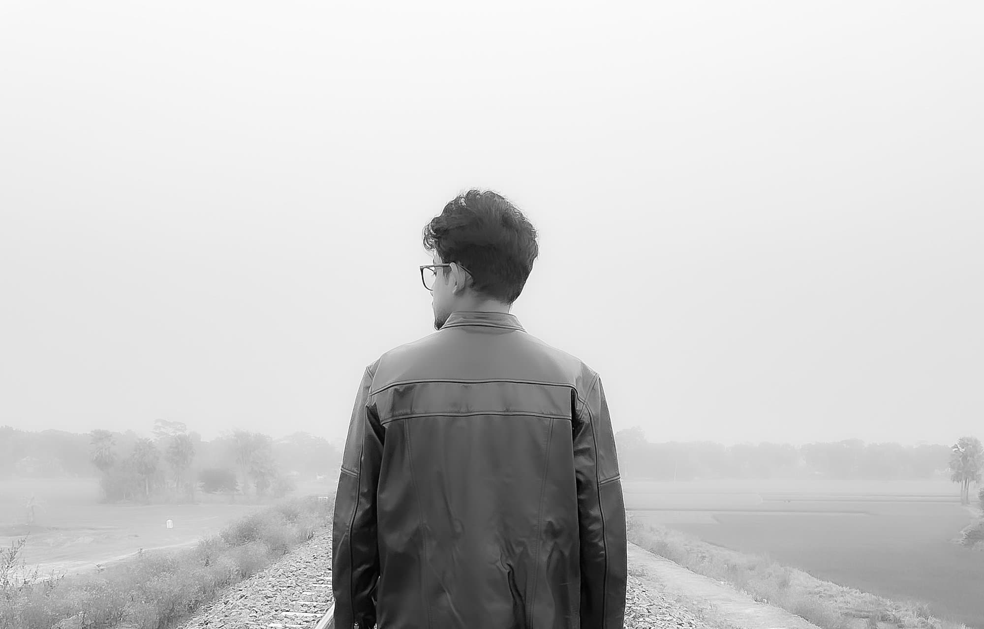 Rabbin Zaman standing with his back turned, looking out over a foggy field.