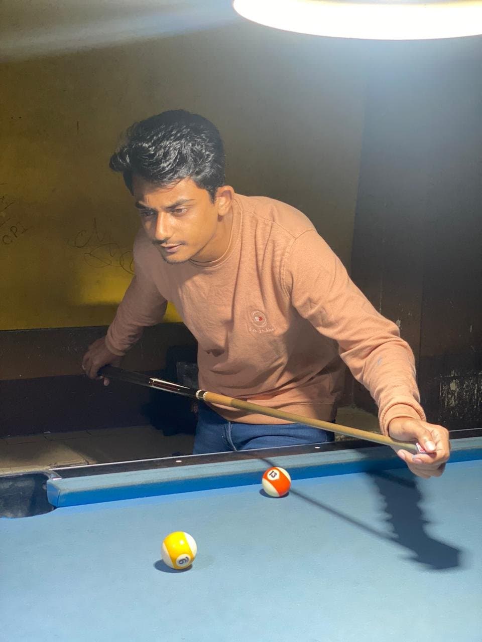 Rabbin Zaman lining up a shot at a billiards table.