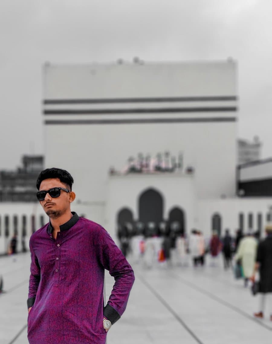 Rabbin Zaman standing in front of a large white building while travelling.